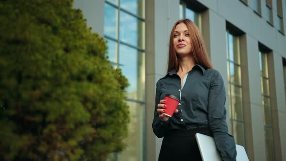 Young Business Woman Drinking a Coffee Laptop in Hand