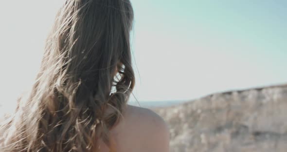 Woman with Blowing Hair Walking Among the Cliffs and Turns at Camera