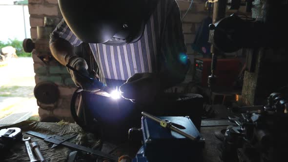 Repairer Welding Some Detail of Auto. Mechanic Working in Garage or Workshop with Welding Machine