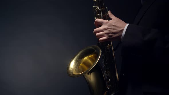 Saxophonist plays the blues saxophone while pressing the valves in the studio on a gray background,