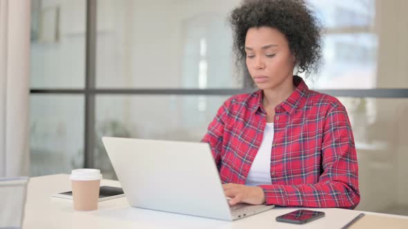 African Woman Looking at Camera While Using Laptop