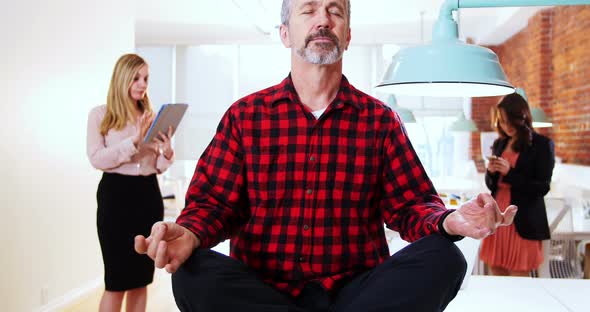 Male executive performing yoga while his executive standing in background