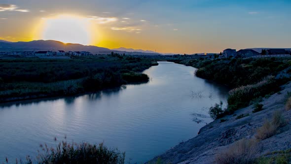 Static time lapse of a beautiful river and ladscape at sunset as the scen transitions to night