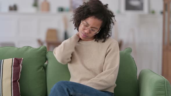 Tired African Woman with Neck Pain Sitting on Sofa