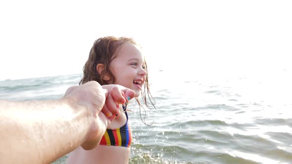 Three year old girl pulls her dad's hand with the gesture of following me.