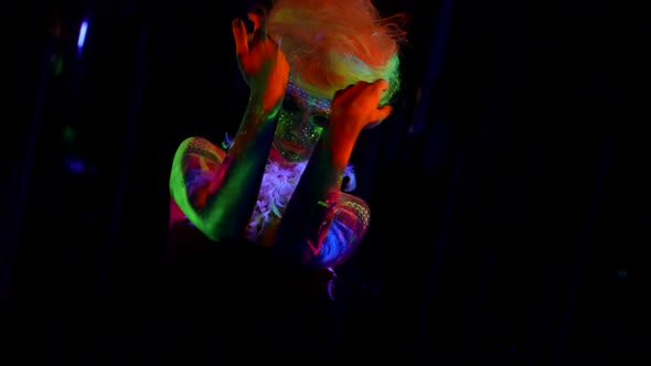 Lady with Eccentric Makeup By Fluorescent Paints and Neon Wig on Head UV Light