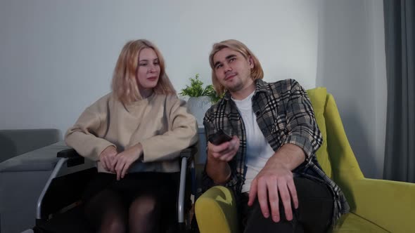 Young Man and Woman in a Wheelchair Sitting in Living Room