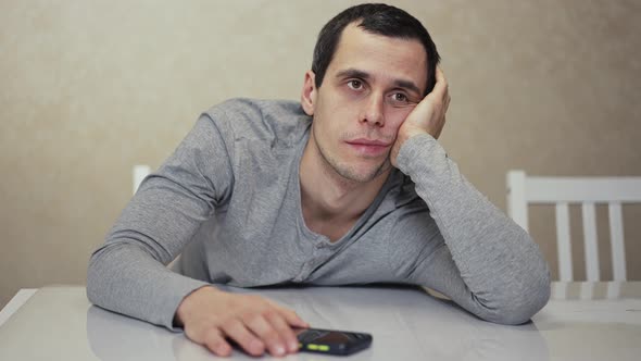 Man Waiting for a Phone Call Sitting at the Table