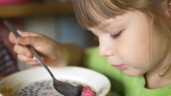 Young Pretty Girl Catches Berries in Milk with Metal Spoon