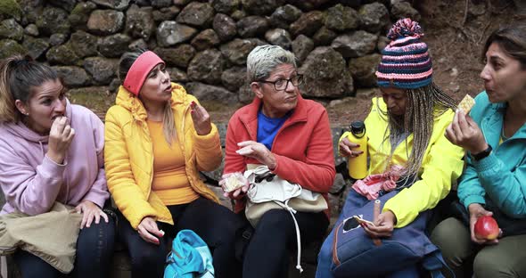 Multiracial women eating a snack during trekking day