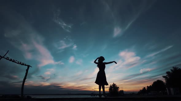 Silhouette of a Ballerina Dancing Against the Sunset Sky. Girl Dancing and Spinning on Tiptoe