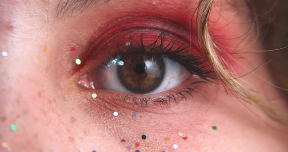 Close up of brown eyes blinking with glitter