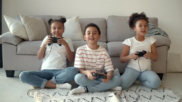 Happy African American Kids Playing Video Game with Joystick at Home