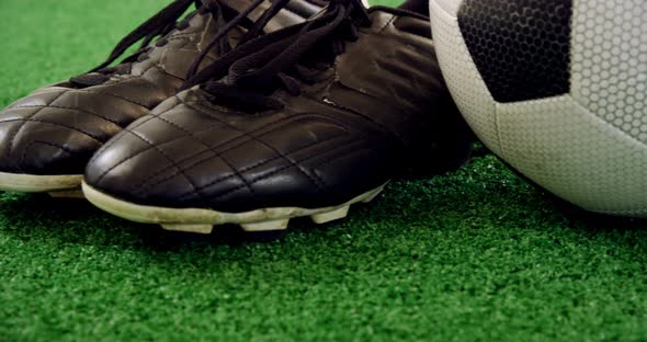 Football and cleats on artificial grass 4k