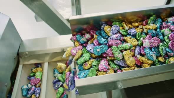 Candy Factory. Bunch of Wrapped Candies Falling From Conveyor on Packing Containers in Confectionery
