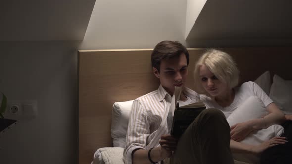 Young Couple in Love Lying in the Bed and Reading Book