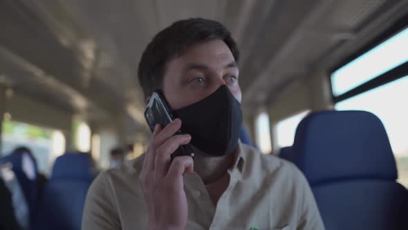 Masked Male Calling Someone on Phone on Train in the New Normal