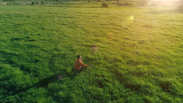 Low Altitude Radial Flight Over Sport Yoga Man at Perfect Green Grass. Sunset in Mountain.