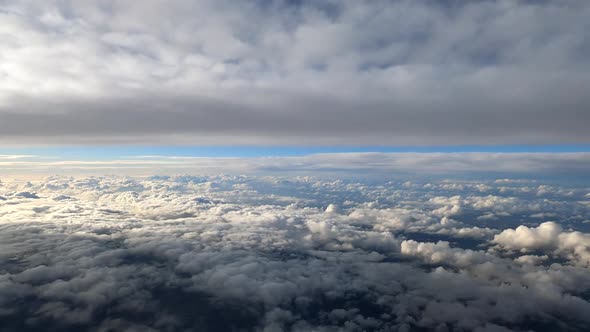 Flying above sunny layers of white clouds in the blue sky, from airplane