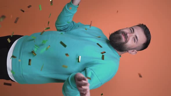 Vertical video, a guy throws up a handful of confetti