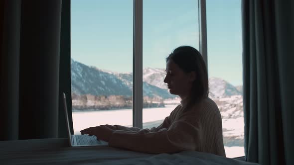 Woman Freelancer Working From Home Sitting in the Bedroom By the Window