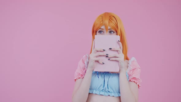 Redhaired European Timid Teenager Hiding Her Face Behind Pink Diary Pink Background Medium Studio