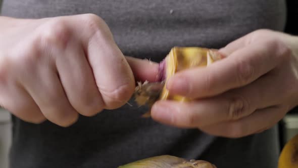 Woman Cleaning Heart of Artichokes with Spoon