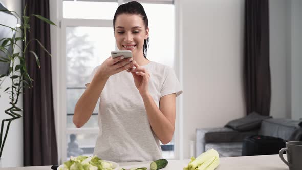 A beautiful woman using her mobile while taking photo of salad