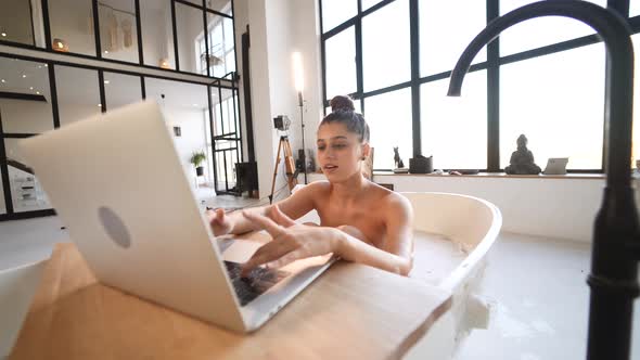 Young Woman Working on Laptop While Taking a Bathtub