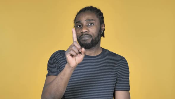 Casual African Man Waving Finger to Refuse Isolated on Yellow Background