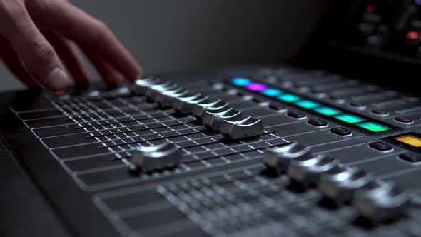 Man Works on a Professional Electronic Audio Mixer. A Control Panel for Tuning Sound Channels