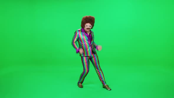 Retro Dude in a Multicolored Suit is Dancing a Funny Dance on a Green Background a Festive Mood a