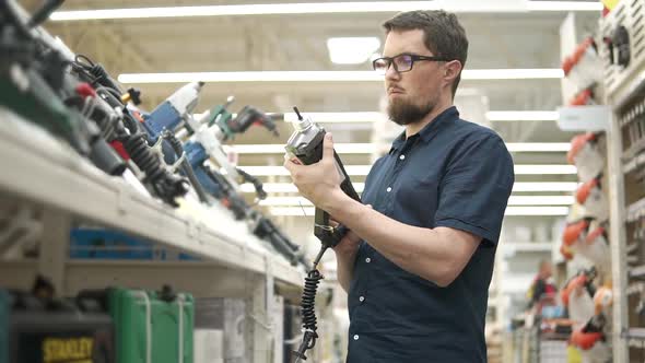 Male Customer is Checking a Hammer in a Shop of Building Tools