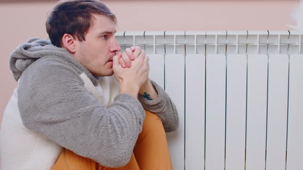 Man Sitting on Floor and Warming Near Radiator