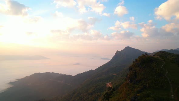 The rays of the sun shine through the clouds into the misty above the mountains in the morning