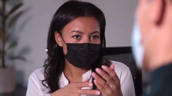 Businesswoman Talking to Man and Sitting at Table in Modern Office During Pandemic Spbi