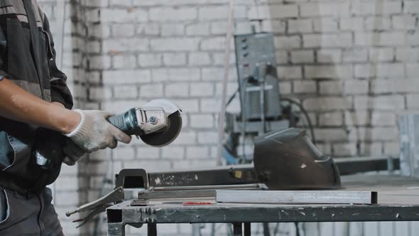 Young Man Working at Manufacturing Plant  Grinding the Metal Construction