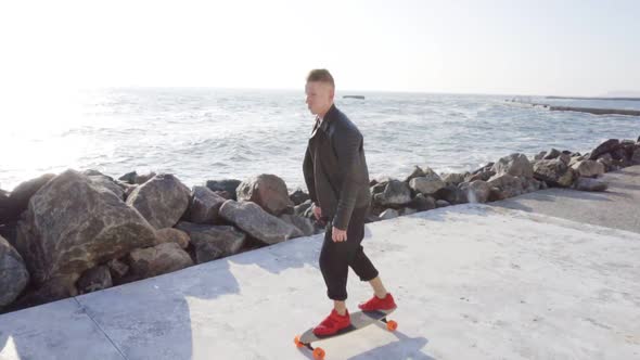 Young Man Rides His Longboard By the Sea