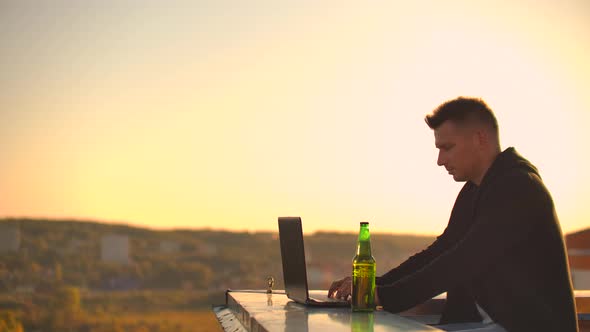 Hipster Man with a Laptop on the Edge of the Roof. Freelancer at Work. Wireless Mobile Internet