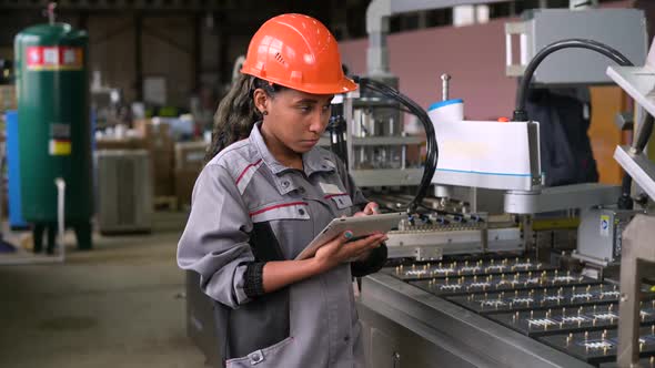 A young black manufacturing worker controls an assembly line in a factory