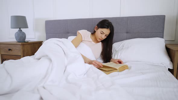 Woman Reading A Book On Bed