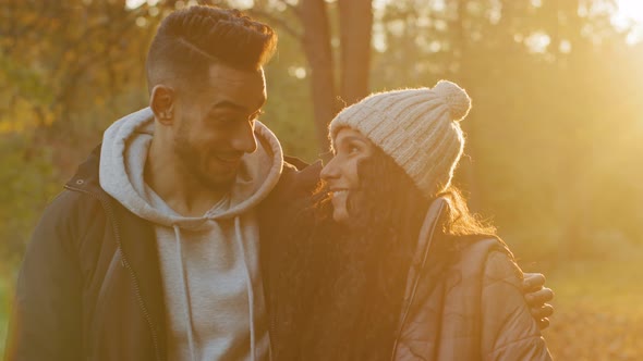 Young Happy Couple in Love Standing Outdoors Hugging Admiring Sunset in Sunshine Talking Smiling