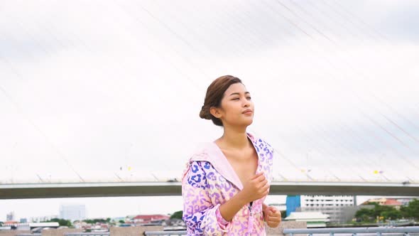 Asian Lady Running on Riverside on Cloudy Day