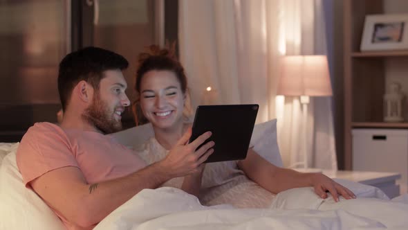 Happy Couple Using Tablet Computer in Bed at Night 23