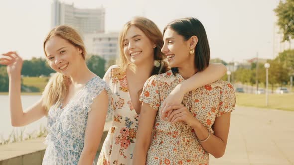 Three young beautiful girls posing outdoors at summer sunny day