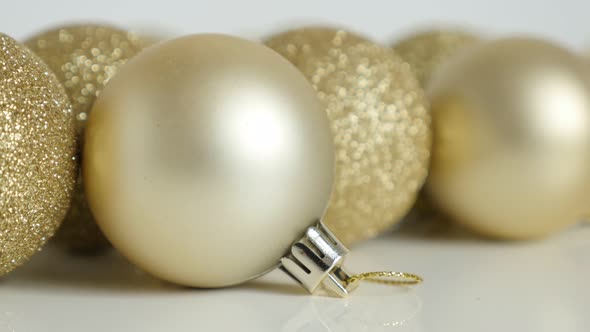 Golden Christmas baubles on white close-up 4K  footage