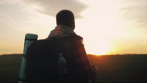 Silhouette Hiker Man Tracking with Backpack and Trekking Pole at Sunset on the Background. Alone