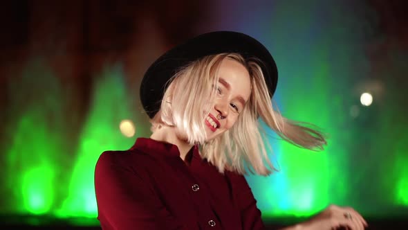 Portrait of Charming Charismatic Hipster Woman with Blond Hairstyle Standing on Neon Fountain