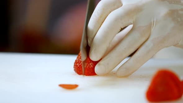 Hand with Knife Cutting Strawberry.