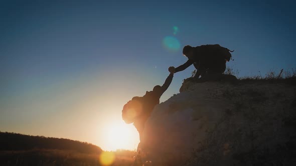 Silhouette of Helping Hand Between Two Climber. Two Hikers on Top of the Mountain, a Man Helps a Man